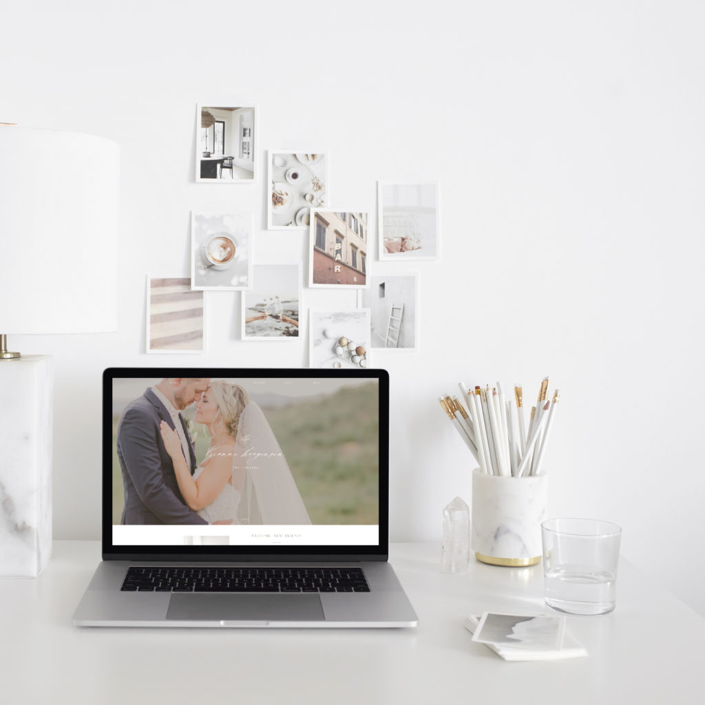 A white desk with neutral accessories and a laptop displaying Brianne Haagenson Photography's new website design.